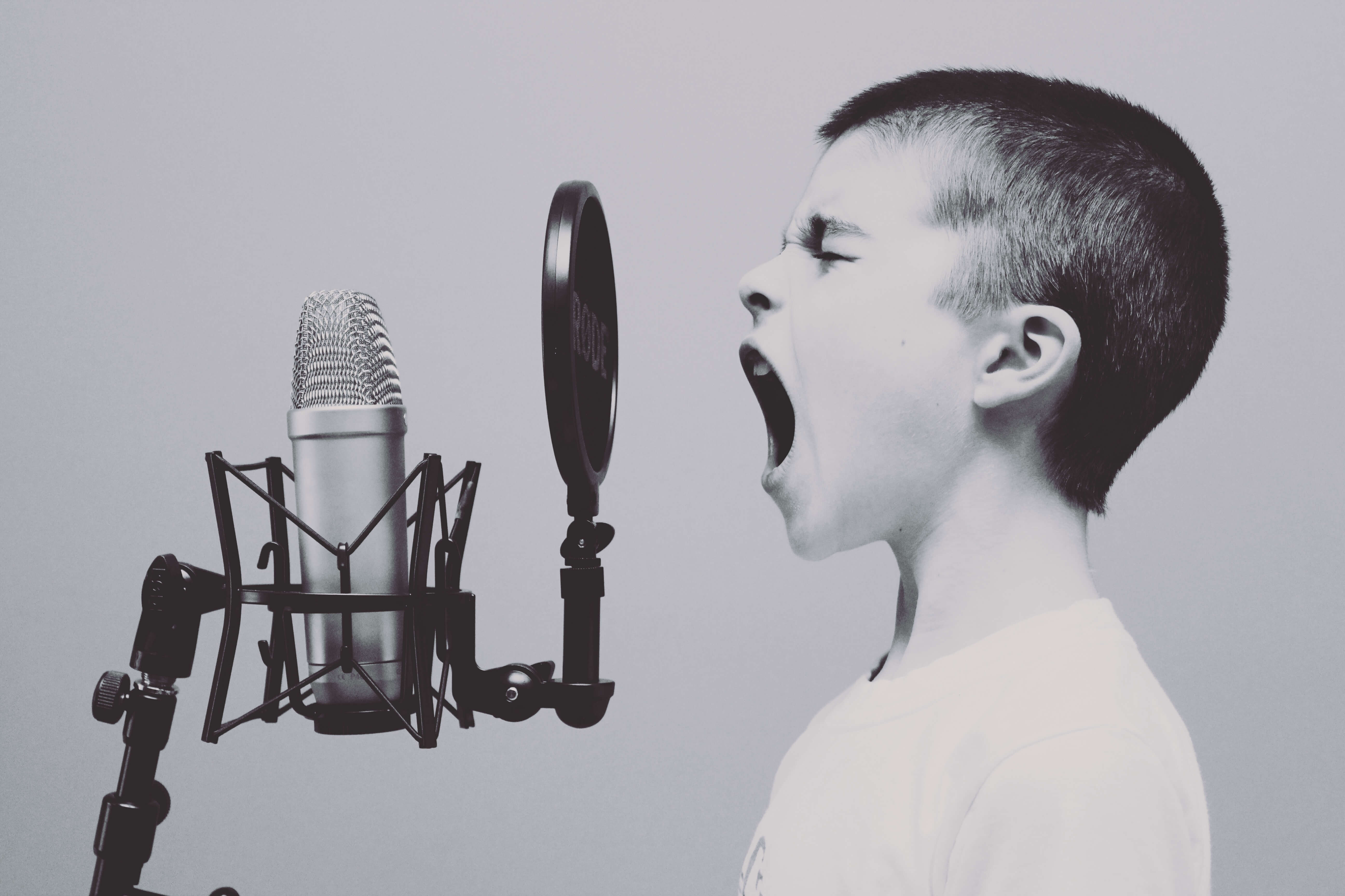 black and white image of a child shouting into a professional stage mic