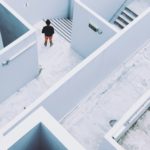 person pausing in a maze of white walls and stairs