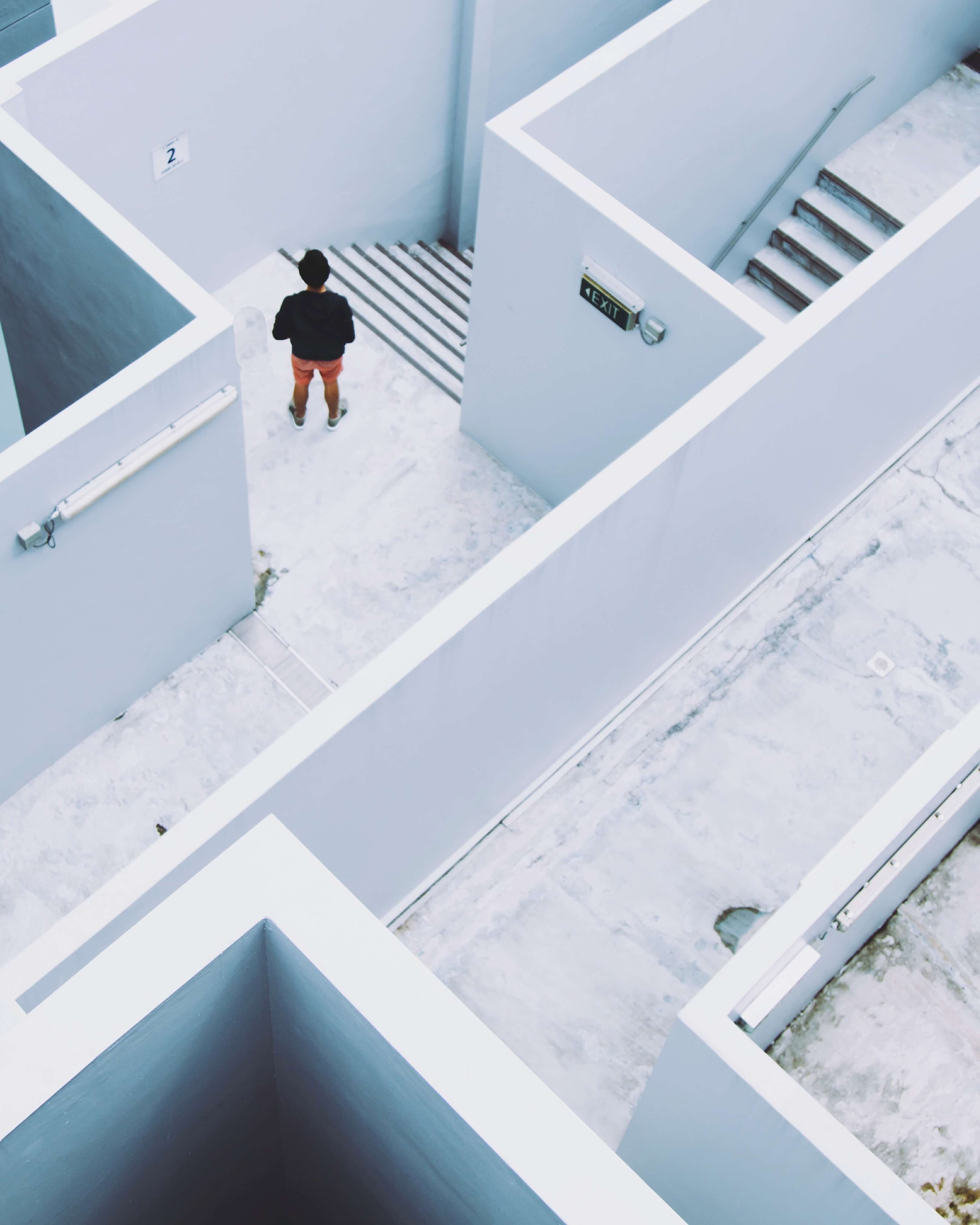 person pausing in a maze of white walls and stairs