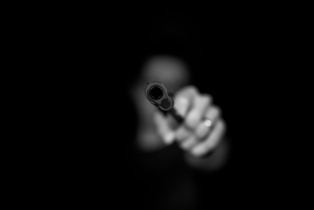 blurry man in shadows pointing a gun