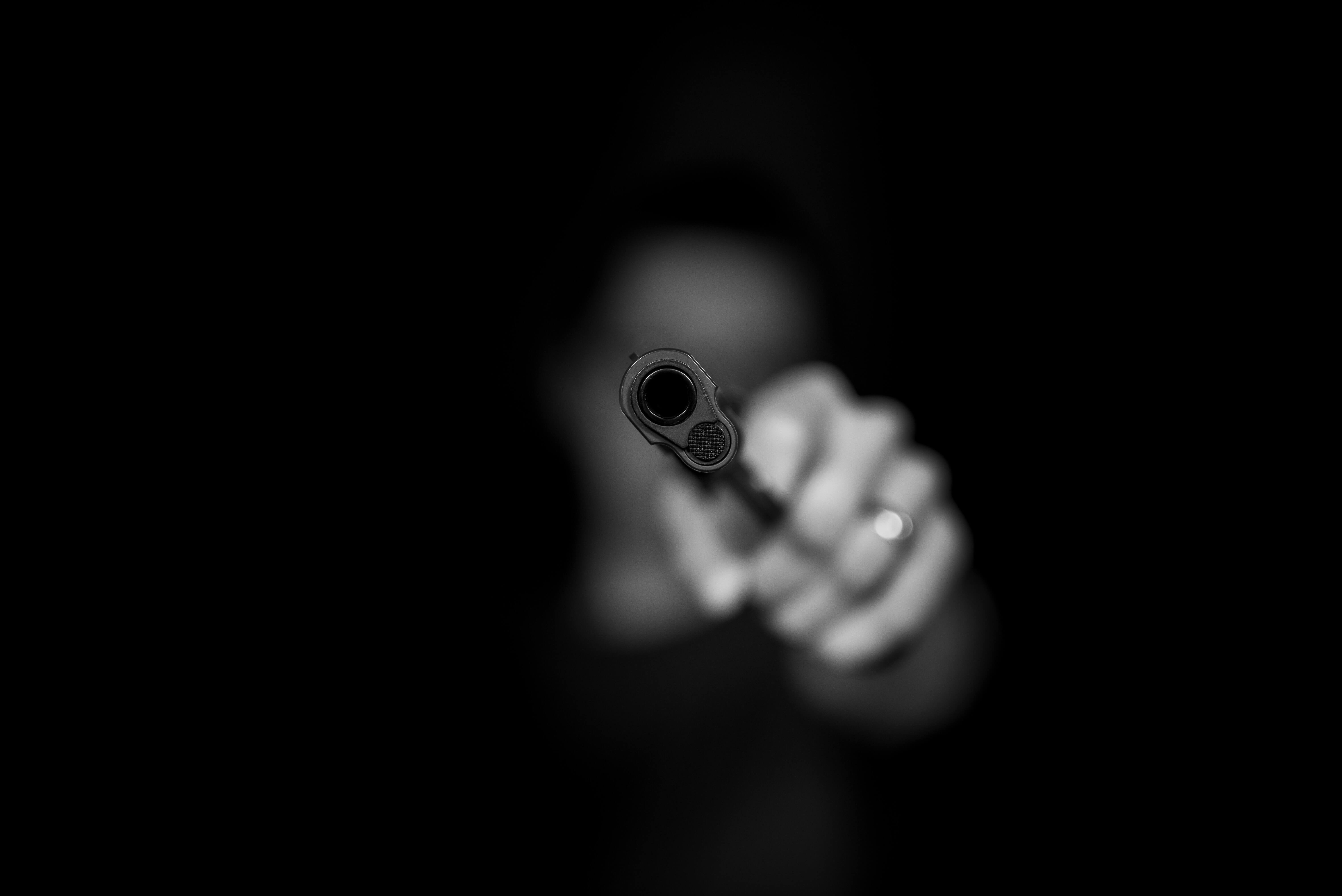 blurry man in shadows pointing a gun
