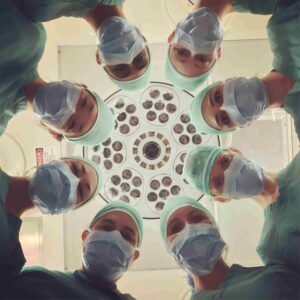 view from an operating table looking at ceiling as 8 people in surgical attire loom over you