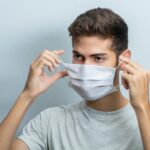 man putting a protective mask over mouth and nose