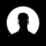 white man's face silhouetted by spotlight