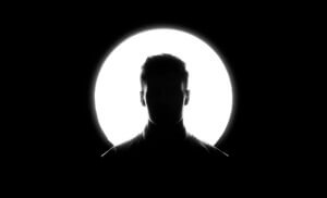 white man's face silhouetted by spotlight