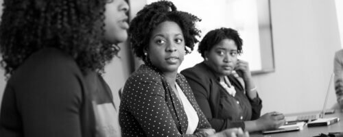 B&W image of three black women seated at a conference table