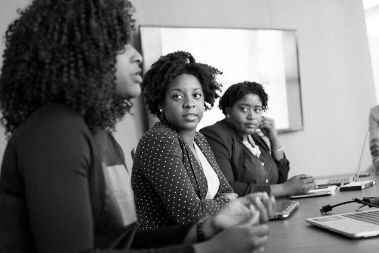 B&W image of three black women seated at a conference table