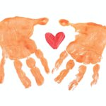 finger-paint style image of two brown hands framing a red heart
