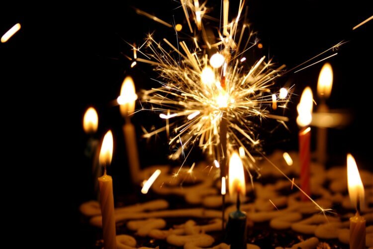 Close-up view of top of a birthday cake in a dark room, focusing on the candles including a sparkler candle