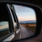 a road and horizon as seen through a side-view mirror of a moving car
