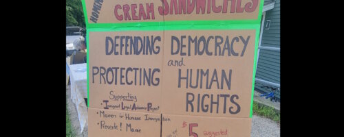 Cardboard sign for a fundraising ice cream sandwich sale that reads, in part: "Homemade Ice Cream Sandwiches" "Defending Democracy and Protecting Human Rights"