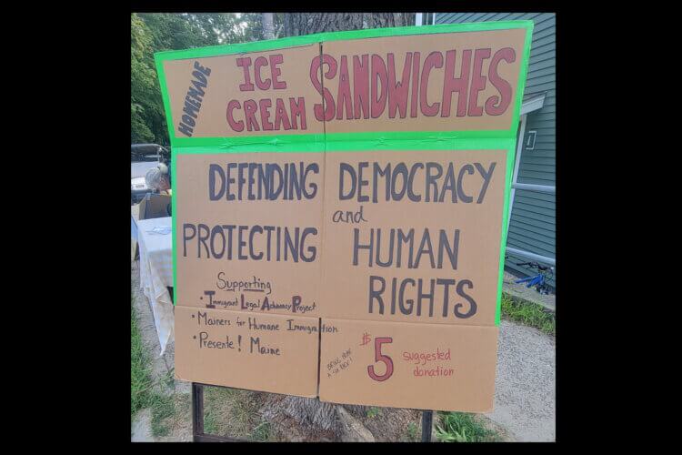 Cardboard sign for a fundraising ice cream sandwich sale that reads, in part: "Homemade Ice Cream Sandwiches" "Defending Democracy and Protecting Human Rights"