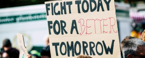 A sign held aloft at a protest reading: FIGHT TODAY FOR A BETTER TOMORROW