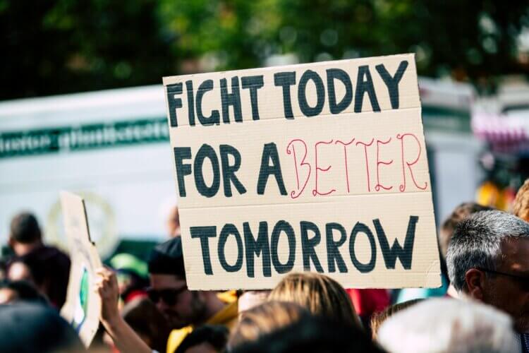 A sign held aloft at a protest reading: FIGHT TODAY FOR A BETTER TOMORROW
